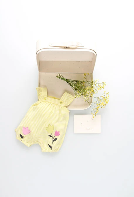 Grenouillère en tricot pour bébé fille de couleur jaune à rayures avec un motif de fleurs.