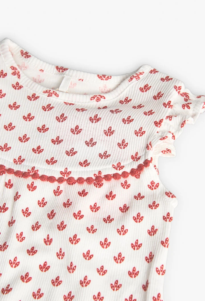 Combinaison en tricot pour bébé fille de couleur blanche avec un motif de fleurs rouges.