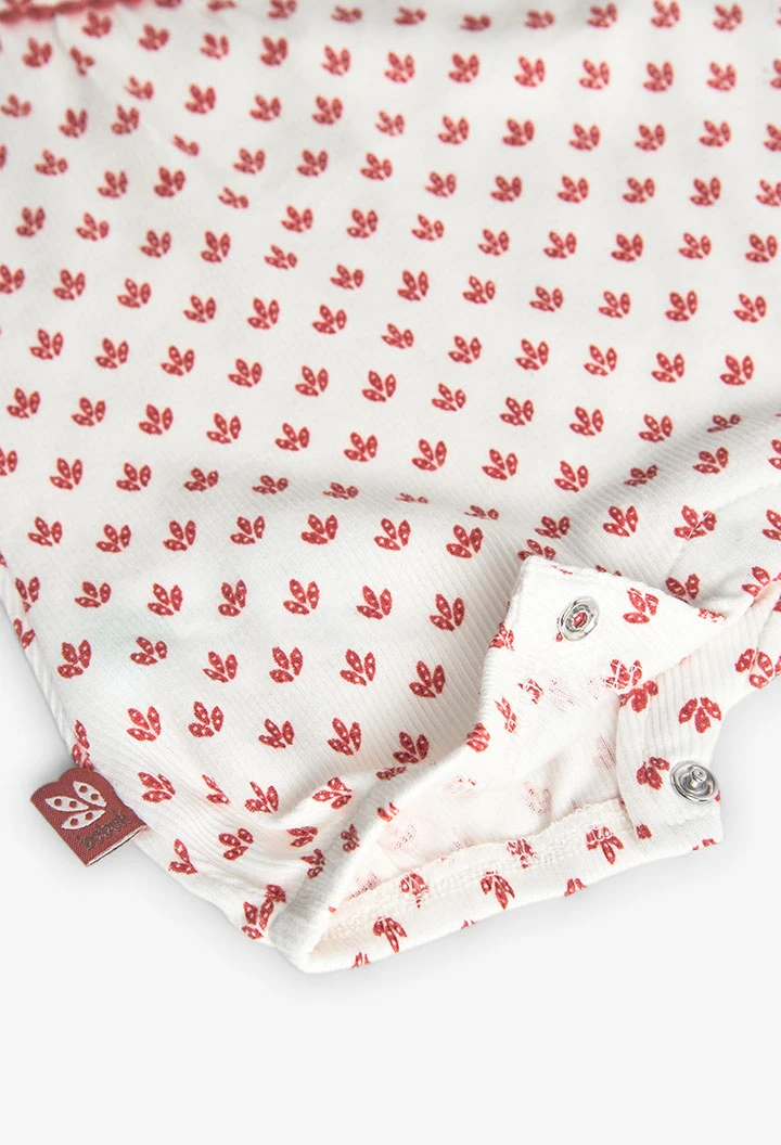 Combinaison en tricot pour bébé fille de couleur blanche avec un motif de fleurs rouges.
