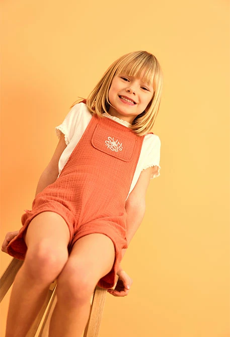 Pagliaccetto a maglia per bambina in colore arancione.