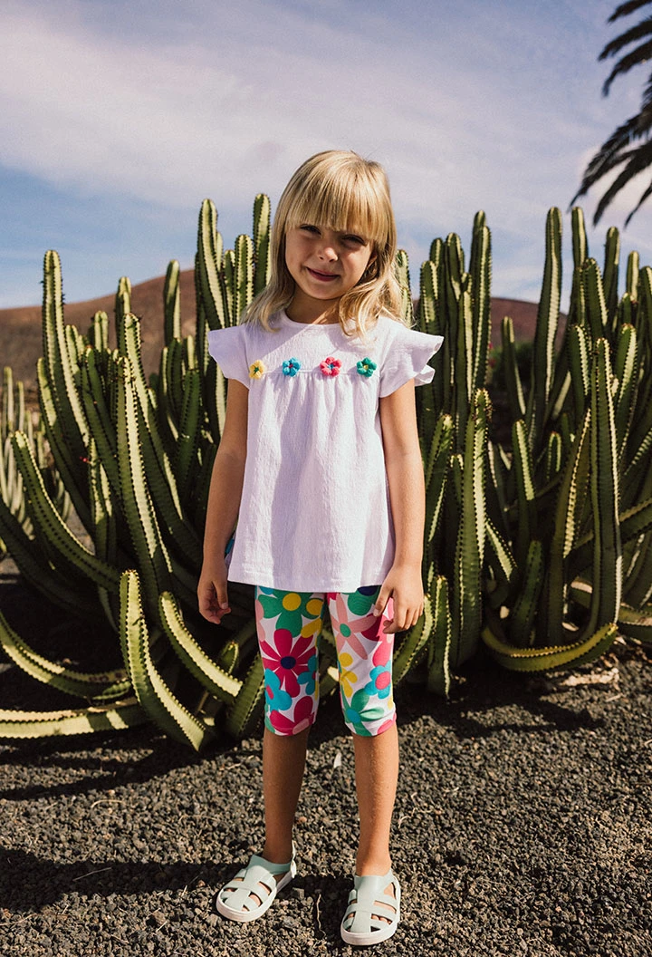 Maglietta a maglia per bambina in colore bianco con design di fiori ricamati.