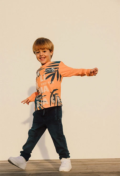 Maglietta a maglia per bambino in arancione a maniche lunghe.