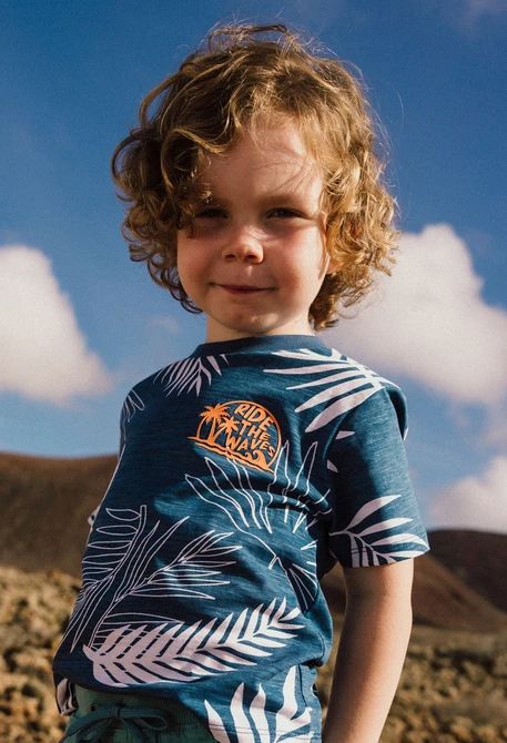 Maglietta in maglia per bambino di colore blu con design tropicale.