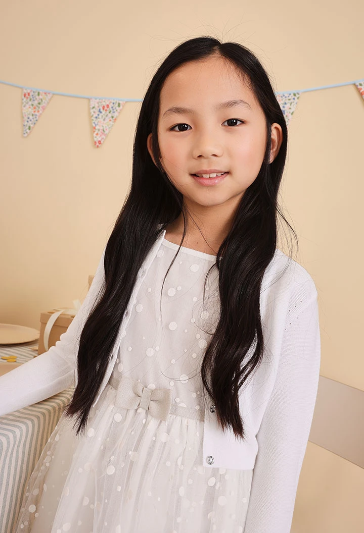 Veste en tricot pour bébé fille de couleur blanche.