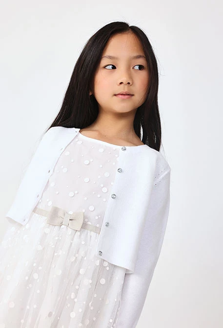 Veste en tricot pour bébé fille de couleur blanche.